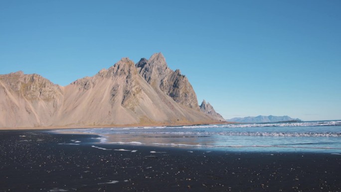 海浪冲刷着陡峭的Vestrahorn山峰下的黑色沙滩。