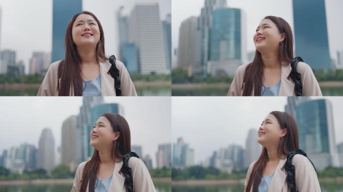 快乐的年轻亚洲女性站在户外看城市景观。自信快乐美丽的年轻女子仰望城市街道，梦想，思考或美好的未来。生