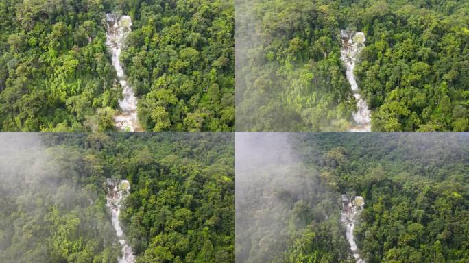 从空中俯瞰琅勃拉邦的热带森林树木环绕的光寺瀑布。后拉镜头与倾斜，通过云层揭示森林景观