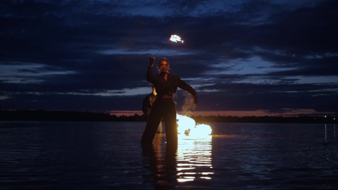 火，水和黑暗的惊人表演，女人站在河里或湖里和火焰玩耍