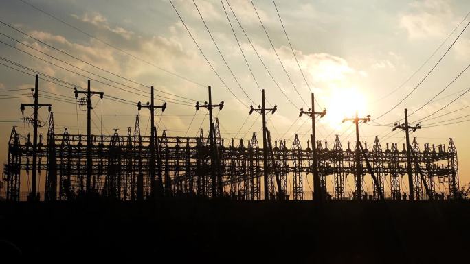 在黄昏的微光中，电力生产和分配中心的剪影视图。能源概念电力枢纽和金色戏剧性太阳。