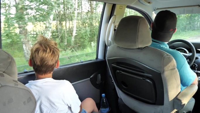 男孩从开着的车窗往外看。一家人在度假时用曼尼什语周游全国。夏天的时候，这家人会开着他们的小货车旅行。