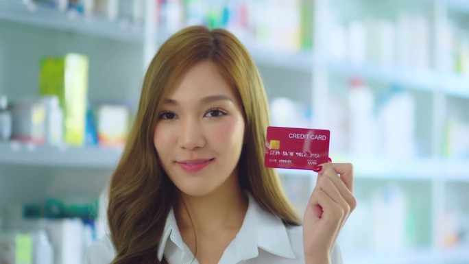 美女在药房手里拿着信用卡。