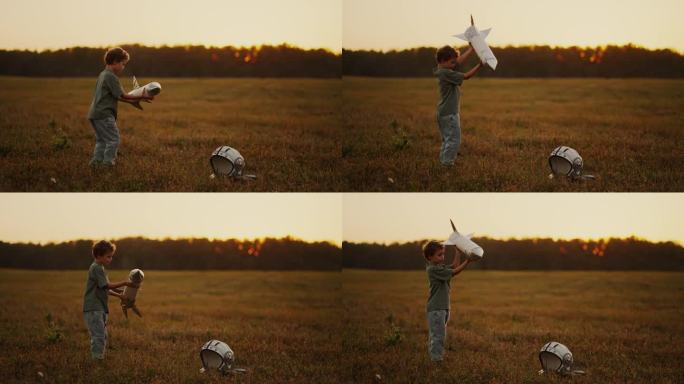 大自然中的小男孩，夏天在田野里玩玩具火箭和太空头盔的孩子，慢镜头