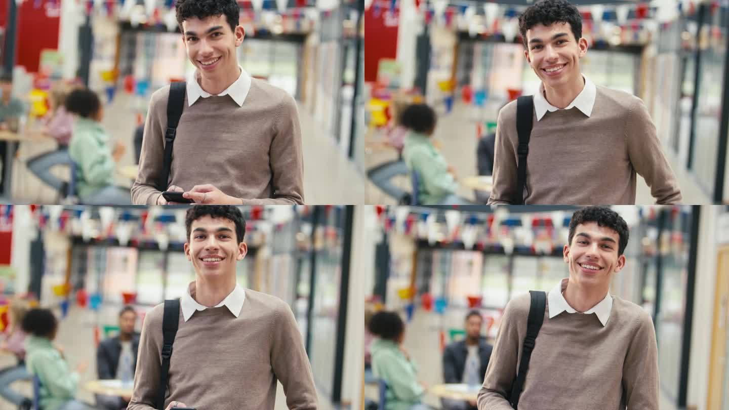 微笑的男大学生站在大学大楼里用手机的肖像