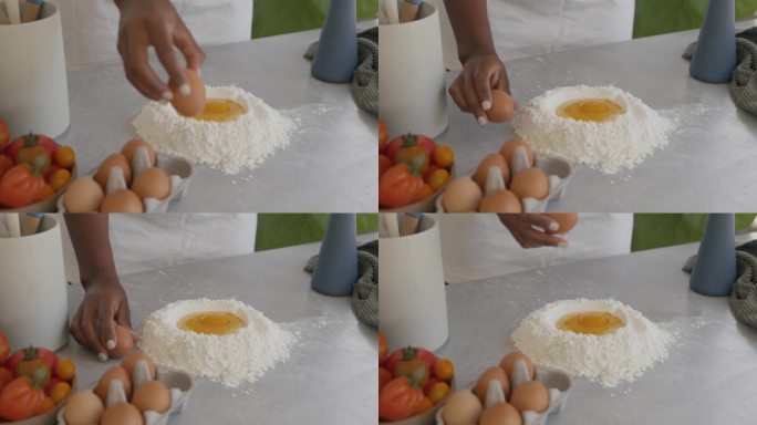 一名妇女把鸡蛋敲成面粉，做面食或面包的面团