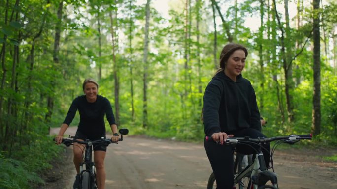 快乐的年轻女子在森林里骑自行车，正面看微笑的女性面孔，积极的情绪