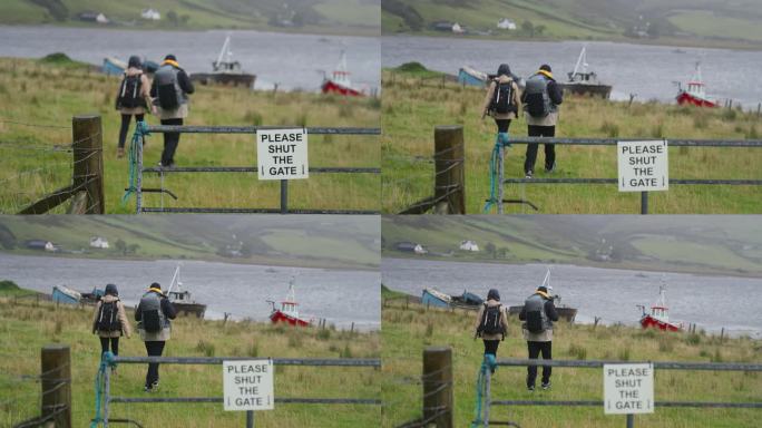两个人一起徒步旅行。驶往湖边码头的渔船。牌子上写着“请关上大门”