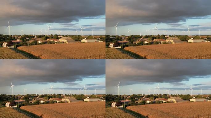 风力涡轮机在蓝天的映衬下转动，天空上是深灰色的风暴云，雨在法国村庄的视线之下。