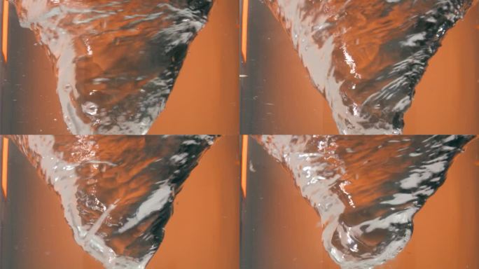 一个旋转或盘旋的水漩涡或水龙卷风在橙色背景前的静态慢动作镜头
