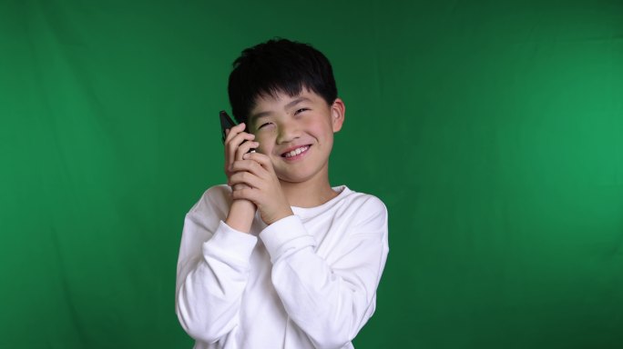 绿色背景下小男孩使用智能手机打电话慢镜