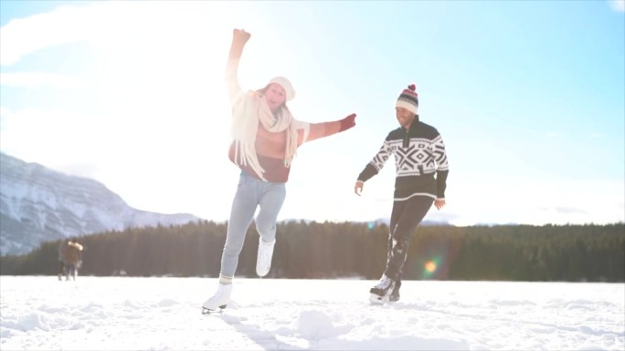 幸福的年轻夫妇手牵手在冰湖上滑冰，享受冬天的乐趣