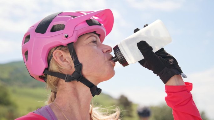 在一个阳光明媚的日子里，女山地自行车手从水瓶里喝水