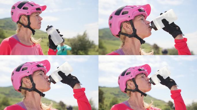在一个阳光明媚的日子里，女山地自行车手从水瓶里喝水