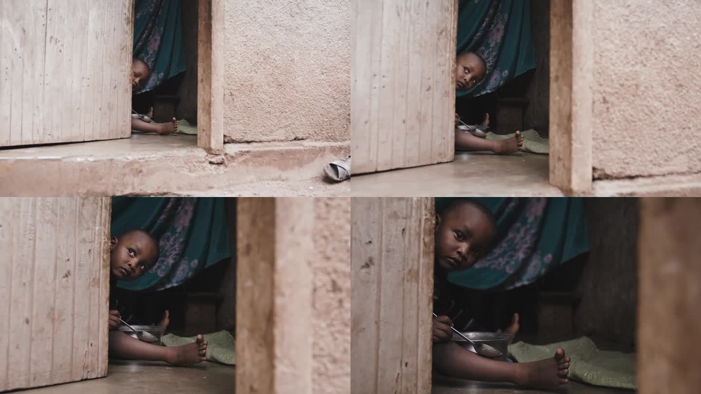 从门口看到男婴的慢镜头。蹒跚学步的孩子坐在屋子里从门口偷看。他在门口。农村黑人儿童代表美好未来的希望