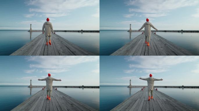 一个人在美丽海湾的木制码头上独自行走的后视图，看到灯塔，慢动作