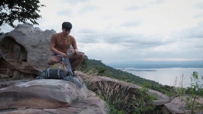 年轻的亚洲男子徒步旅行者带着背包，喜欢看山顶上的山水山谷湖景