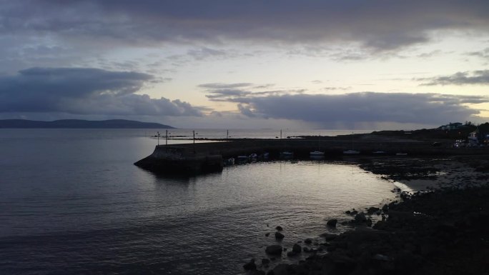 黄昏时分，无人机从爱尔兰戈尔韦的巴纳码头撤退，光线反射在海洋上