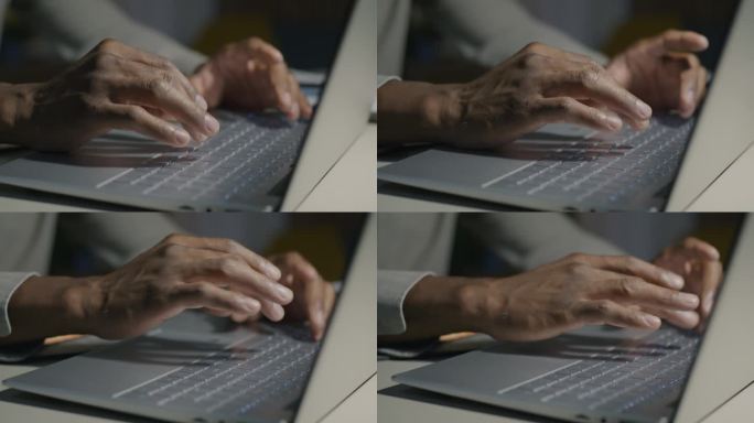 男性用笔记本电脑键盘打字的特写，而非裔美国程序员晚上在办公桌前编码