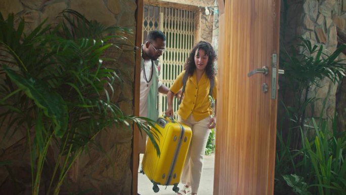 兴奋的不同的夫妇带着行李箱进入豪华度假别墅