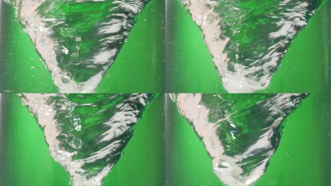 在绿色背景下，一个旋转或盘旋的水漩涡或水龙卷风的静态慢动作镜头