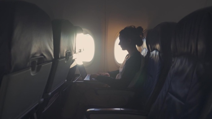在飞机上用笔记本电脑工作的女人