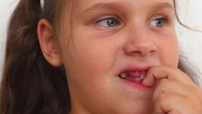 体贴，紧张，情绪化紧张的金发小女孩用手指在没有牙齿的嘴里剔牙。清洁乳牙