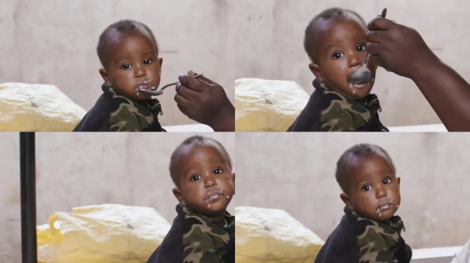 可爱宝宝吃食物的慢镜头。母亲给儿子喂饭的残缺的手。他们在门廊边。农村黑人儿童代表美好未来的希望，呼吁