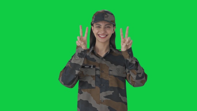 快乐的印度女军官在绿屏上展示胜利的手势