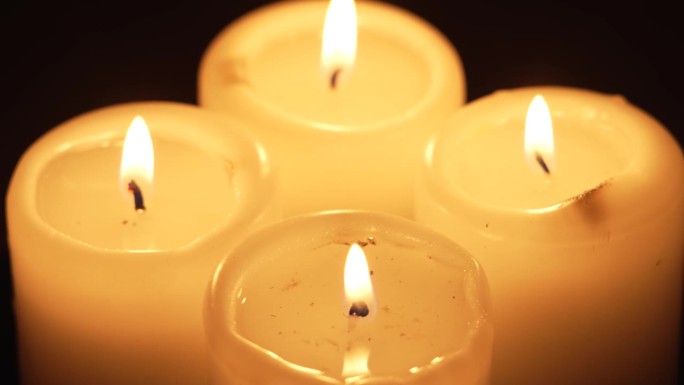 燃烧的四支蜡烛芯火焰近距离旋转在黑暗的背景