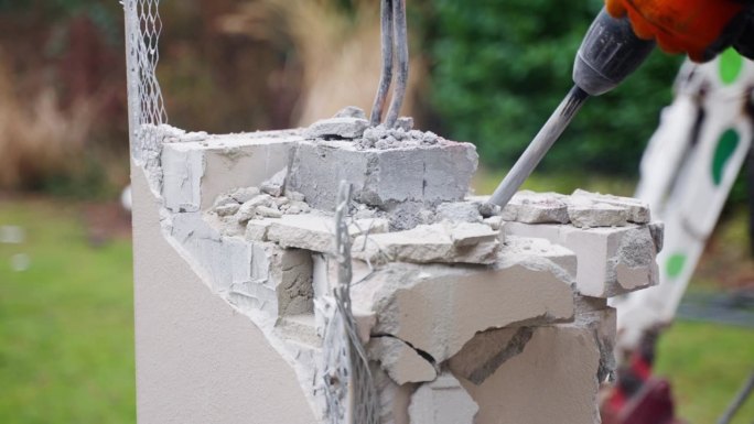 人做房子重建，用手提钻拆墙，砖碎，灰泥飞