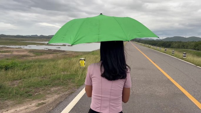 女子在雨中撑着一把绿伞。