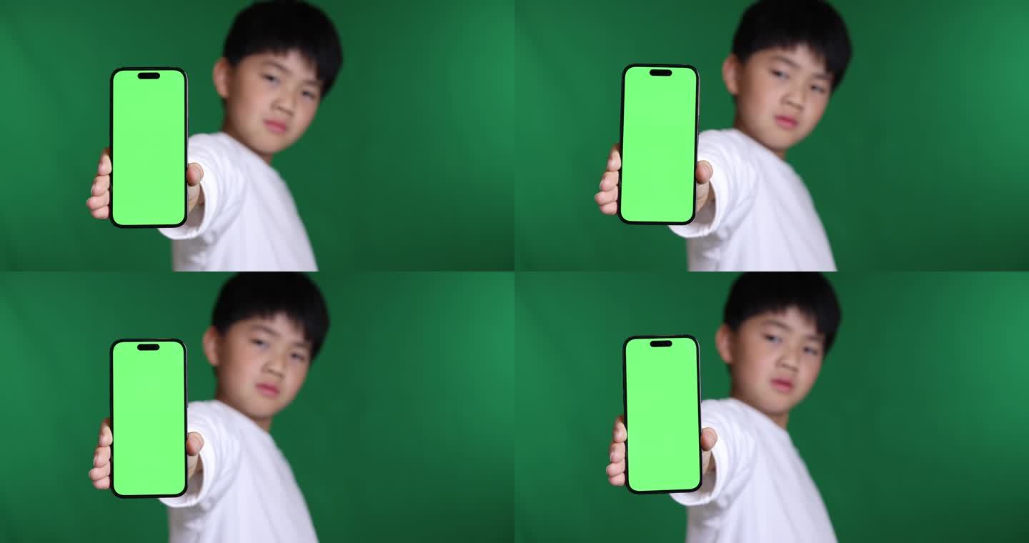 可爱的中国小男孩展示绿屏智能手机