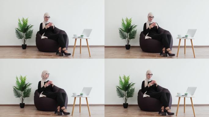 一个女人在工作场所的软靠椅上休息时拿着手机