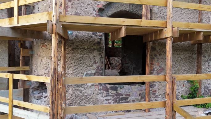老旧的石头城堡塔楼正在修复中，由手工搭建的木制脚手架包裹着。