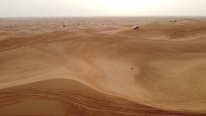 在迪拜沙漠的沙丘上行驶的汽车鸟瞰图。
