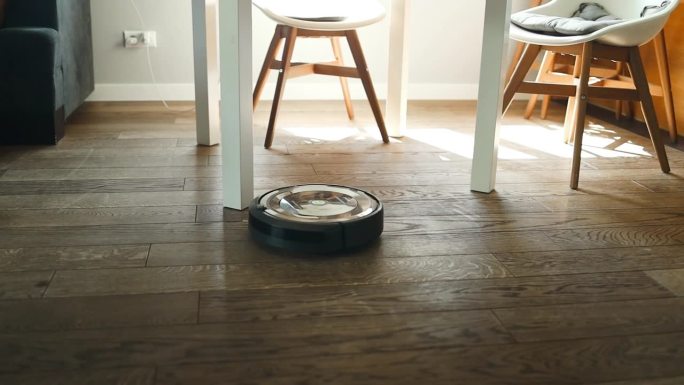 机器人吸尘器正在卧室里吸尘。拥有自动化设备的智能家居，简化生活。智能吸尘器可以清洁地板。