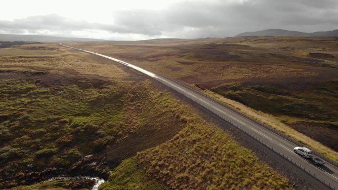 冰岛，日落时分，一辆白色轿车行驶在宽阔的道路上。