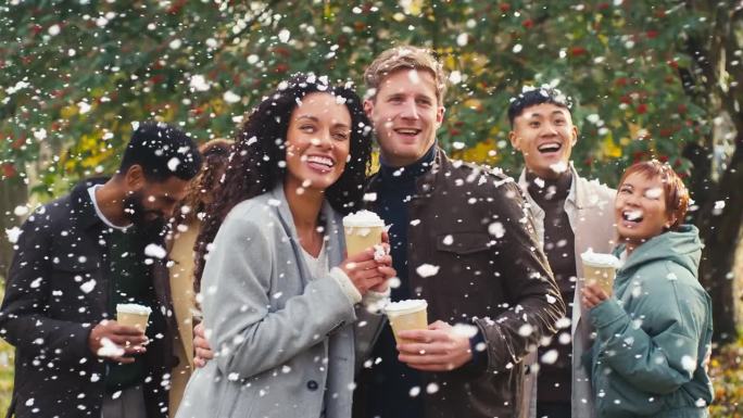 一对夫妇和朋友在雪地里穿着外套，拿着外卖热巧克力饮料