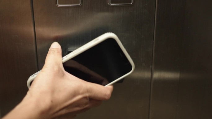 女士用智能手机解锁酒店电梯的手。数字或无密钥验证。