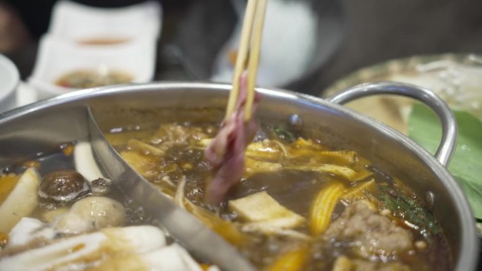 手煮涮火锅式晚餐
吃中餐火锅用筷子夹食物。