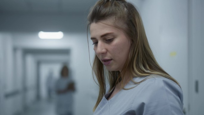 女医生站在诊所走廊，与同事或病人交流
