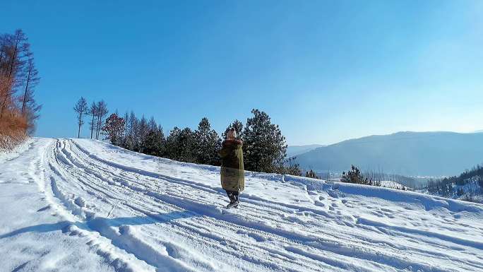 一个人行走在雪山，俯瞰山下小村庄