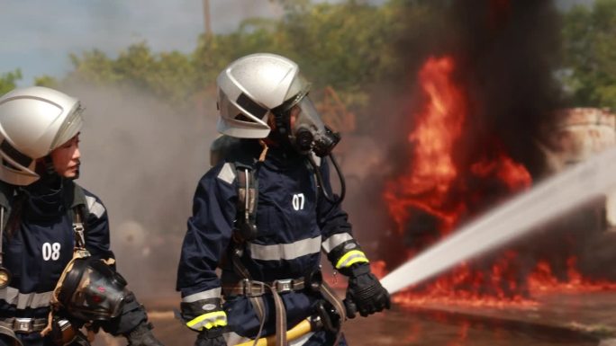 两名专业消防员使用消防水带灭火。
