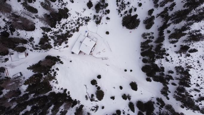 从空中俯瞰冬季积雪覆盖的山坡，树木闪闪发光，奥地利Lehnberghaus的雪屋小屋鸟瞰
