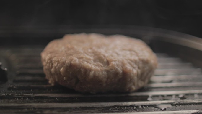 烤架上的牛肉或鸡肉汉堡正在准备美味的汉堡三明治，黑色背景和简单的光线设置在RAW 4K上拍摄