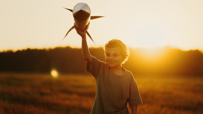 夕阳下无忧无虑的小男孩在田野里玩着玩具火箭，梦想着太空旅行
