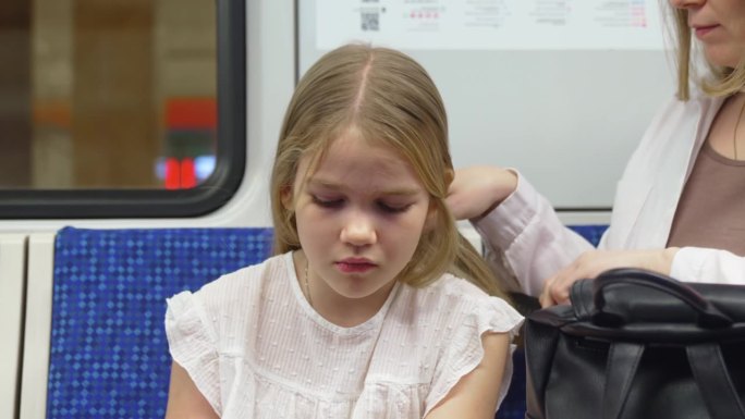 妈妈在地铁里给女儿梳头。