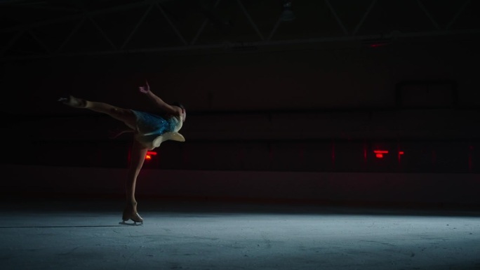 才华横溢的花样滑冰运动员在冰场上表演舞蹈，黑暗中女人的剪影