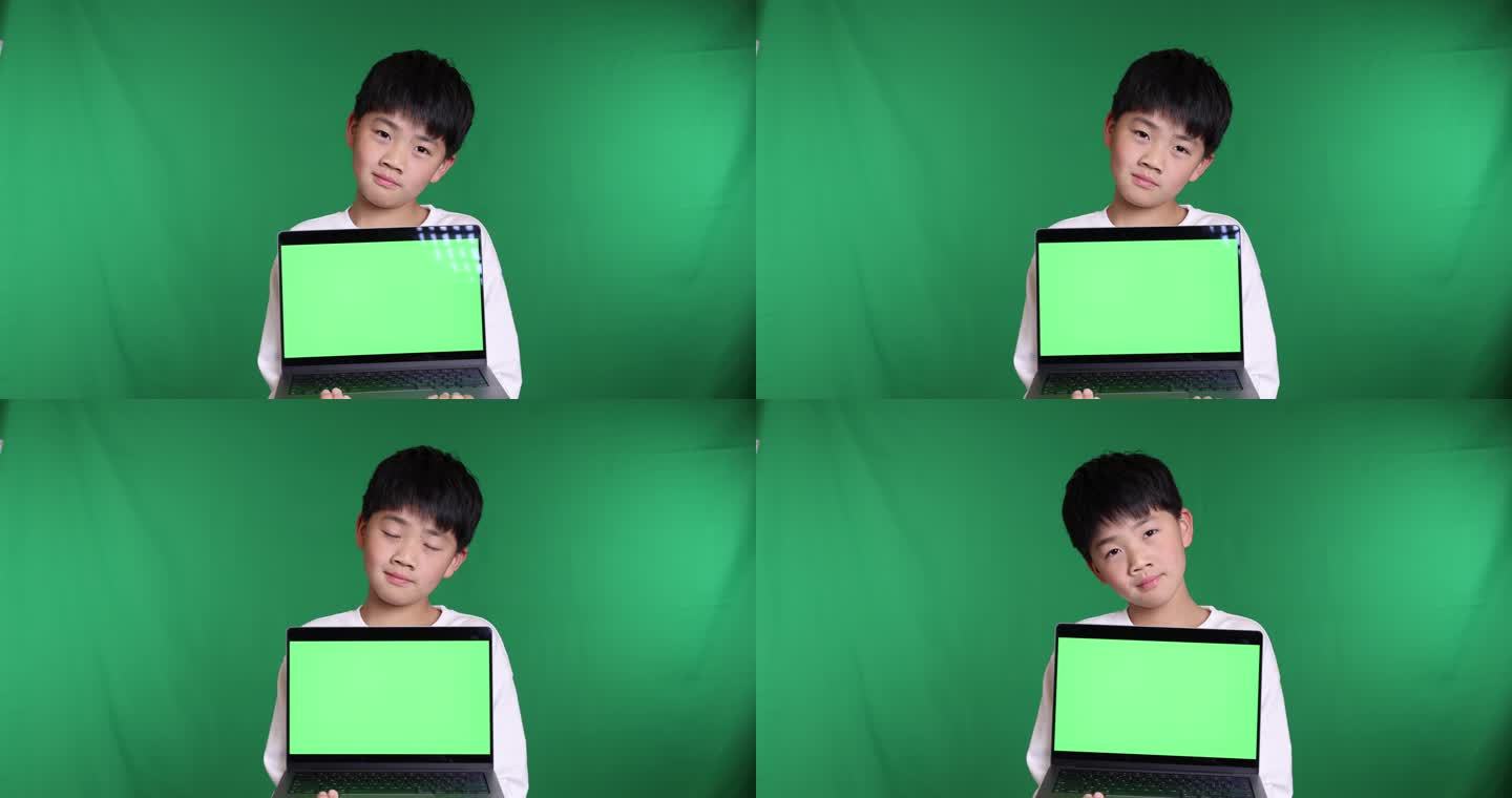 可爱的中国小男孩展示绿屏笔记本电脑